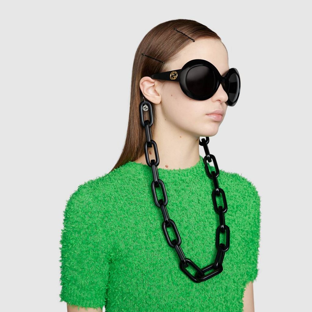 Mannequin femme portant des lunettes de soleil et une maxi chaîne à lunettes en résine - GUCCI